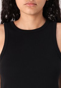 Black ribbed tank top with a high neckline and sleeveless design, made of a smooth, elastic fabric.