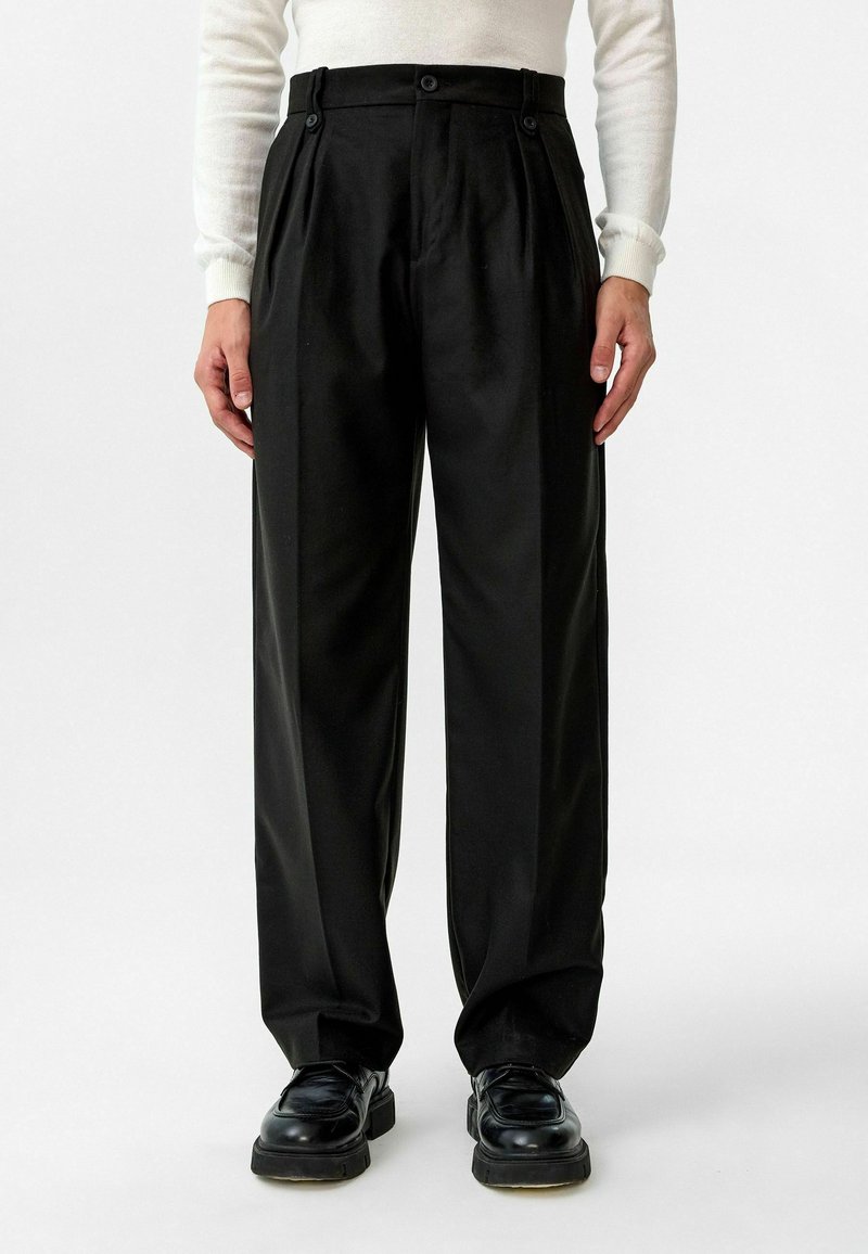 Zwarte broek met plooien, hoge taille en knoopsluitingen. Gemaakt van zachte stof, heeft een relaxte pasvorm en gestreken vouwen.
