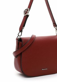Red leather shoulder bag with a textured finish, curved shape, adjustable strap, and silver hardware detailing. Features a logo accent.