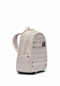 Ανοιχτό μπεζ σακίδιο Nike με δύο κύρια διαμερίσματα, εμπρόσθιο τσεπάκι με φερμουάρ, ρυθμιζόμενους ιμάντες και μαύρο λογότυπο στο μπροστινό πάνελ.