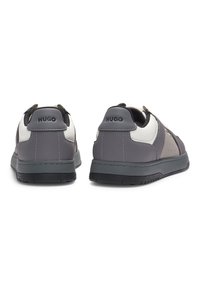 Grey athletic sneakers with a smooth, leather material. Features a reinforced heel, contrasting white accents, and small perforations for breathability.