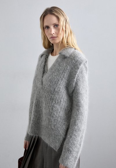 Szürke, textúrált pulóver V-nyakkal és gallérral, puha, bolyhos anyagból készült. Laza szabású és enyhén rövidített aljjal rendelkezik.