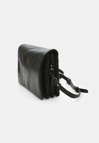 Czarna skórzana torebka na ramię o strukturalnym designie, z klapką zawijaną, metalowymi elementami i odpinanym paskiem na ramię.