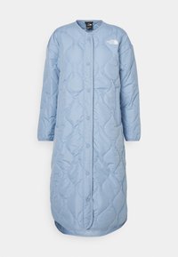 Ljusblå quiltad lång kappa med rund halsringning, tryckknappar, två sidofickor och en liten logga på övre vänstra sidan.