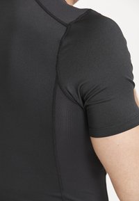 Schwarzes Sportshirt mit glatter Textur, kurzen Ärmeln und kontrastierenden Paneeldetails entlang der Schultern und Seiten.