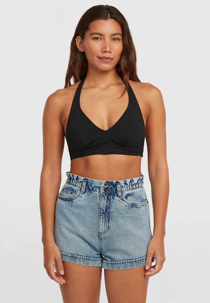 Čierny halter crop top s výstrihom do V a tvarovanými košíkmi, v kombinácii so svetlomodrými denim krátkymi nohavicami s nariaseným pásom a zrolovanými lemy.