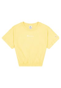 Žluté zkrácené tričko Champion s krátkým rukávem a elastickým lemem, bílé logo na hrudi a malé logo na levém rukávu.