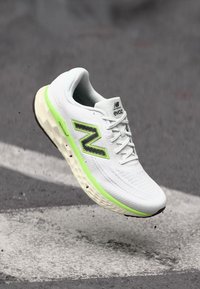 New Balance sneaker with white textile upper, black and neon green accents, textured sole, and a cushioned midsole designed for comfort.