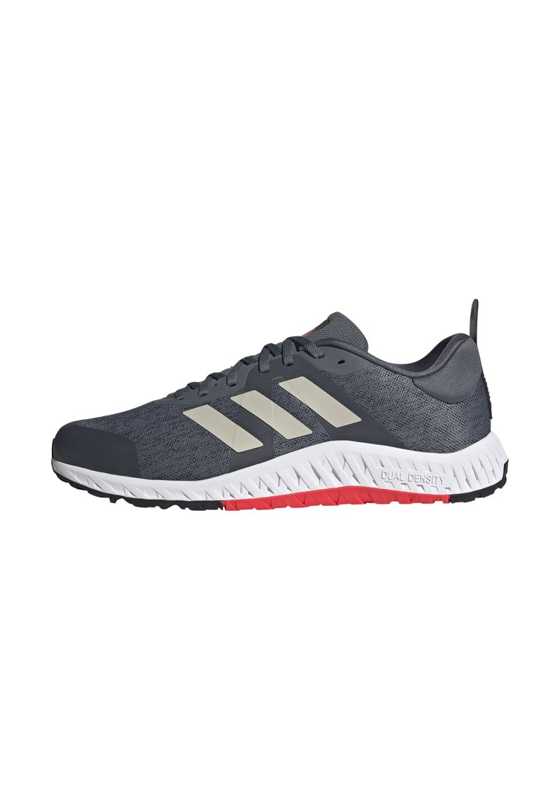 Gray athletic shoe with three white stripes, textured mesh upper, and dual-density sole featuring red and black accents.
