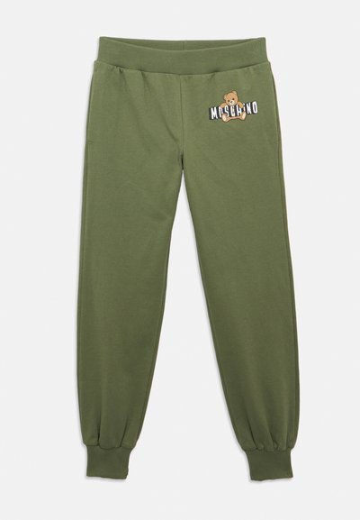 Pantaloni jogger in cotone verde oliva con vita e polsini elasticizzati, caratterizzati da una grafica di un orsacchiotto e dal logo "Moschino" sulla coscia sinistra.