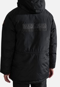 Veste d'hiver noire à capuche vue de dos, avec un grand patch logo "Napapijri geographic" sur le haut du dos.