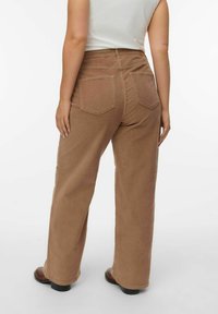 Lichtbruine ribfluwelen broek met een recht model, voorzien van achterzakken en een gestructureerde afwerking. G gedragen met een aansluitend wit topje.