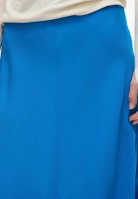 Svetlo modra krilo z gladko teksturo, z nevidnim šivom ob strani in ravno silhueto. Lahka tkanina.