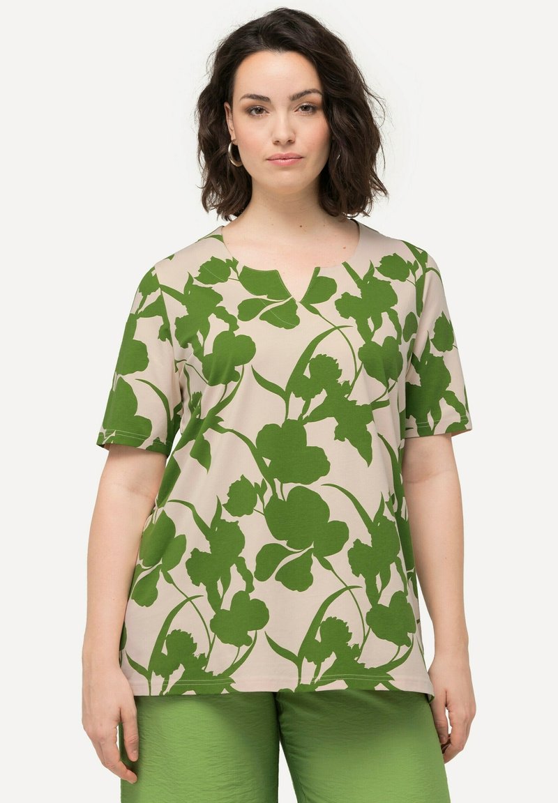 Top a maniche corte, scollo a V in beige con un motivo floreale verde. Tessuto morbido con una vestibilità comoda. Abbinato a pantaloni verdi coordinati.