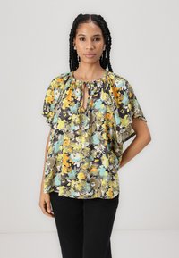Kortermet bluse med blomsterprint på mørk bakgrunn i nyanser av gul, teal og grå. Har nøkkelhullsnæring og løs passform.