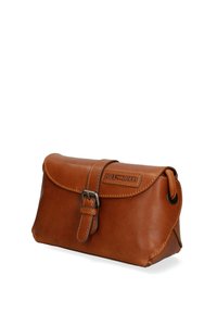 Borsa in pelle marrone con pattina arrotondata, chiusura con fibbia metallica, cuciture color cuoio e una patch in pelle con il marchio. Forma rettangolare compatta.