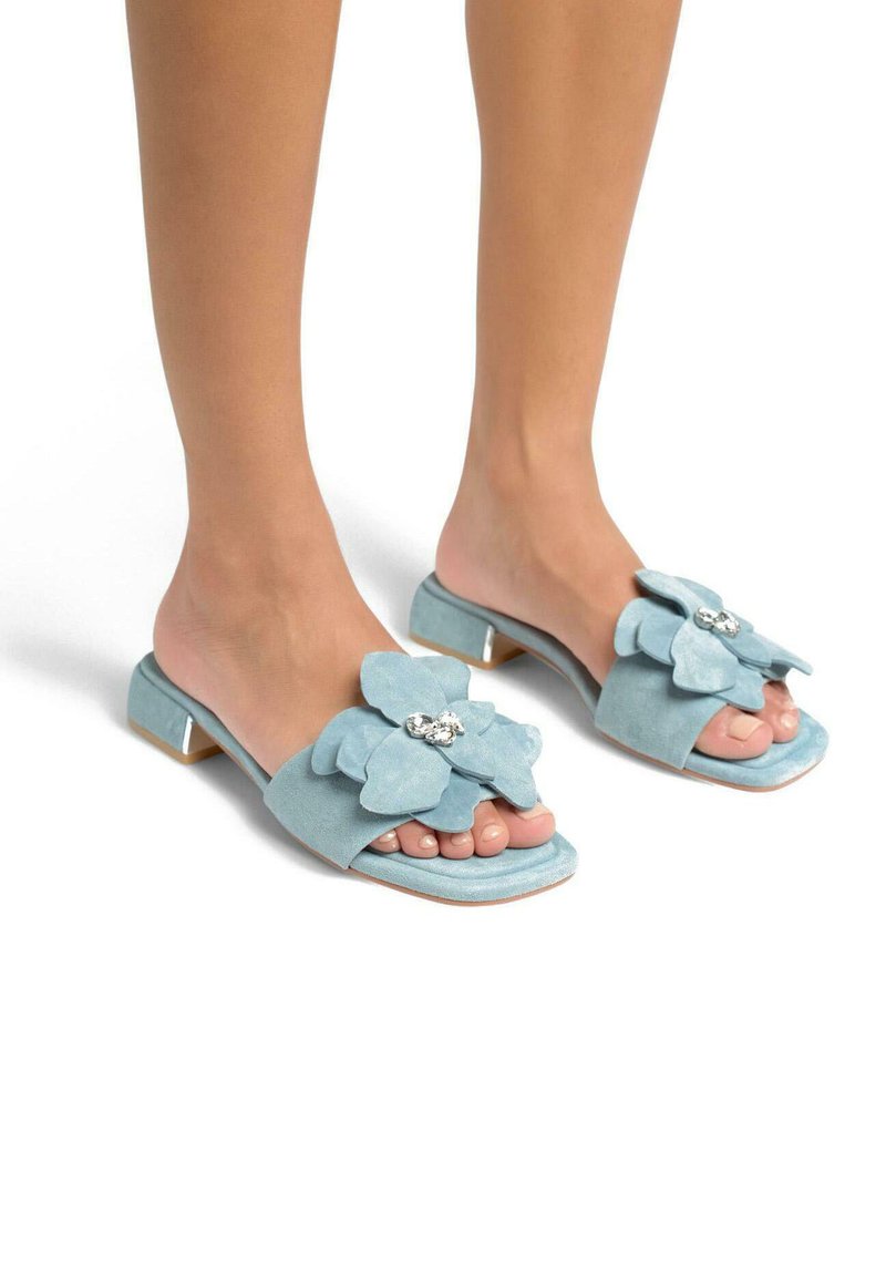 Lichtblauwe suède instapsandalen met een grote bloemenaccent met strasdetails, open teen ontwerp en een lage blokhak.
