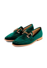 Un par de mocasines de terciopelo verde con suelas marrones y detalle de bitón dorado sobre un fondo blanco.
