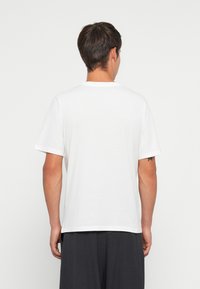 Λευκό T-shirt με κοντά μανίκια από βαμβάκι, με στρογγυλή λαιμόκοψη και άνετη εφαρμογή. Ομαλή υφή, χωρίς ορατά σχέδια ή διακοσμητικά στοιχεία.