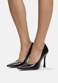 Zwarte lakleren high heels met een puntige neus, met een krokodillenleer textuur en een slanke stiletto hak.