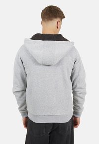 Grijze hoodie met een donkere fleece voering in de capuchon, geribbelde manchetten en zoom, en een ontspannen pasvorm. De achterkant toont een eenvoudig ontwerp zonder extra details.