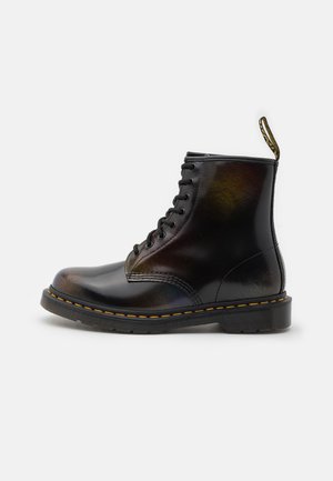 Stivaletto in pelle nera con finitura liscia, punta rotonda, design con allacciatura e accenti di cucitura gialla sulla suola.