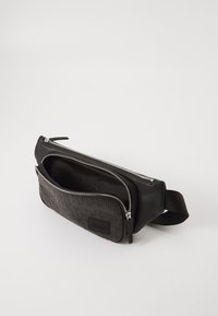 Borsetta in pelle nera con testo "HUGO" in rilievo sulla tasca frontale, zip argentate e cintura nera regolabile.