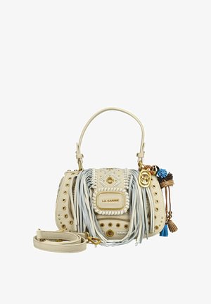 Kleine beige leren handtas met franjes, gouden studs, kwastjes, een bovenhandvat, afneembare schouderriem en decoratieve blauwe en bruine bedeltjes.