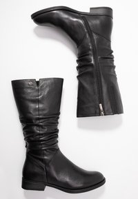 Svarta läderknähöga stövlar med en slapp design som har en siddragkedja och en liten klack, mjuk textur och minimal hårdvara.