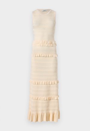 Kootud beež kleit, millel on ëlagis ja kumer kehaosa, rippuvad aktsendid, tekstuuriga triibud ja laienev äär. Kleit on ümmarguse kaelusega ja ilma varrukateta.