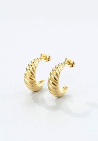 De grandes boucles d'oreilles en or en forme de coquillages spiralés présentent un design texturé avec des nervures, mettant en valeur une finition lisse et des fermoirs sécurisés.
