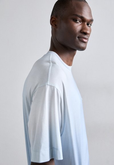 Μπλε γκριάν τυπώματος μπλουζάκι με κοντά μανίκια, στρογγυλή λαιμόκοψη και μαλακή υφή, που διαθέτει ένα διακριτικό λογότυπο μπροστά.