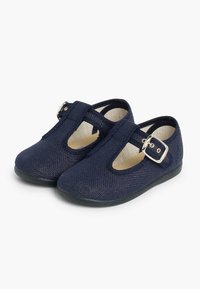 Zapatos Mary Jane de tela azul marino con punta redonda, cierre de hebilla y diseño troquelado en los laterales. Suela plana de goma, parte superior texturizada.