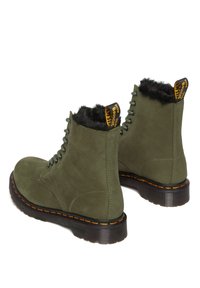 Groene suède enkellaarzen met faux fur voering, ronde neus, vetersluiting aan de voorkant en een dikke zwarte zool met oranje stiksels en een logo-haakje.