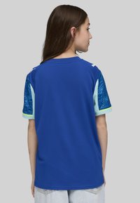 Plava sportska majica s kratkim rukavima, s teksturiranim plavim uzorkom, svijetloplavim naglascima i okruglim izrezom.