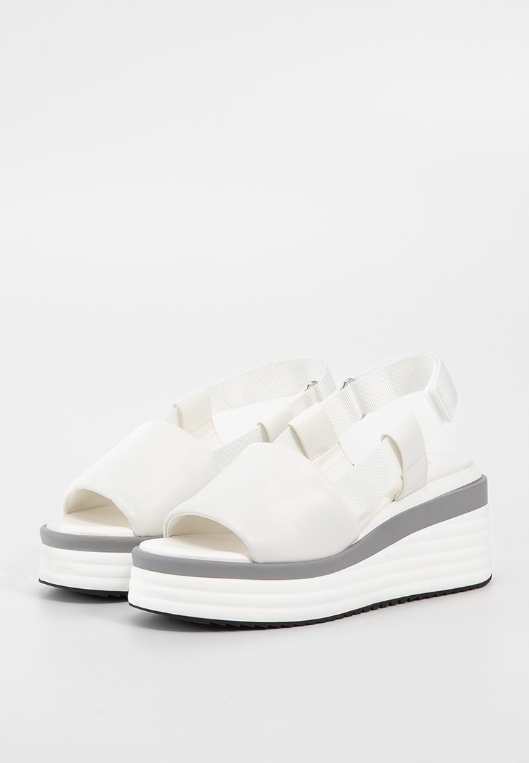 Sandali platform in ecopelle bianca vegan con punta aperta, strisce elastiche e suola a cuneo grigia con fondo testurizzato.