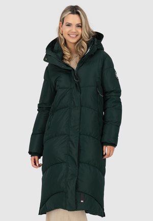 Cappotto imbottito lungo di colore verde scuro con cappuccio. Presenta un design trapuntato, tasche laterali con zip e un'etichetta con logo sulla manica sinistra. Tessuto testurizzato.