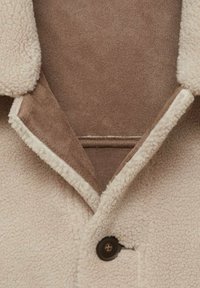 Fleecejacke mit beigem Außenmaterial und braunem Wildlederkragen. Mit Knopfverschluss und einem strukturierten, gemütlichen Stoff für Wärme.