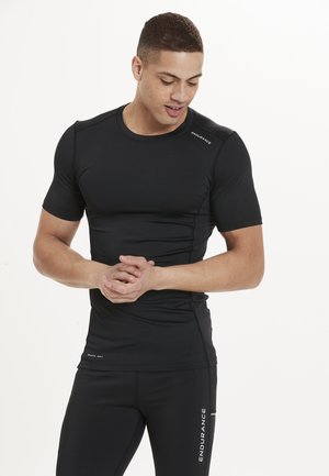 Schwarzes, kurzärmeliges Sportshirt mit figurnaher Passform. Das Material wirkt glatt und dehnbar; mit dezentem Branding an der Schulter und am Saum.