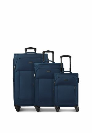 Drei marineblaue Softshell-Koffer in klein, mittel und groß mit ausgezogenen schwarzen Teleskopgriffen und jeweils vier Spinner-Rollen.