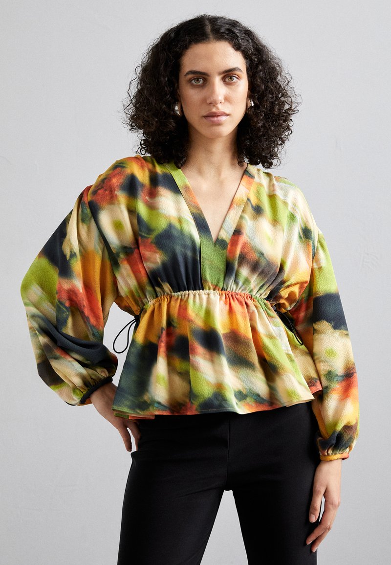 Bluză multicolorată, cu model, cu decolteu în V, talie elastică și mâneci largi, tip balon. Fabricată dintr-un material ușor, având nuanțe de verde, portocaliu și negru.