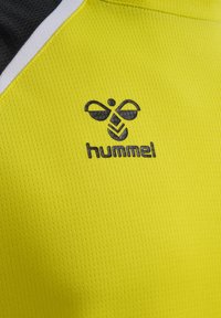 Tessuto sportivo giallo con accenti neri e bianchi che presenta il logo nero hummel e un emblema stilizzato di ape al centro.