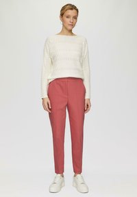 Witte geribbelde gebreide trui met lange mouwen en ronde hals, gecombineerd met een aansluitende roze broek en witte platform sneakers.