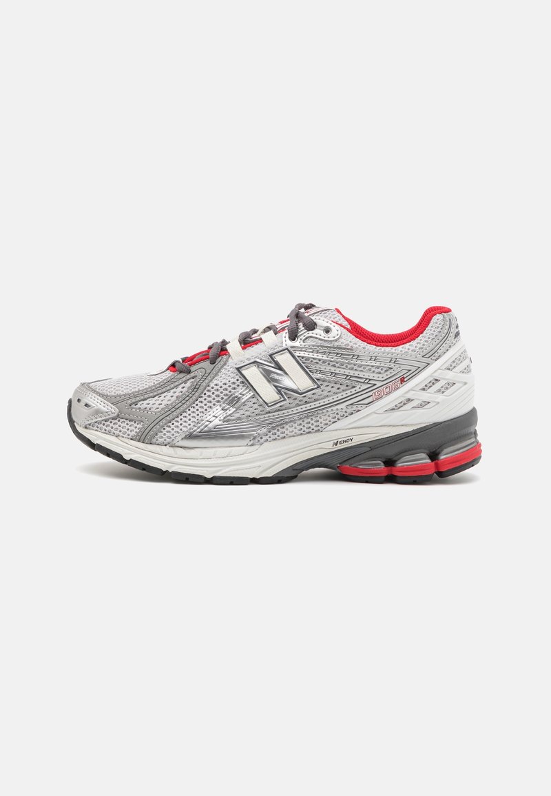 Szare i białe buty biegowe New Balance z czerwonymi akcentami, meshowym wierzchem, wyściełaną podeszwą i etykietą "1906R" po boku.