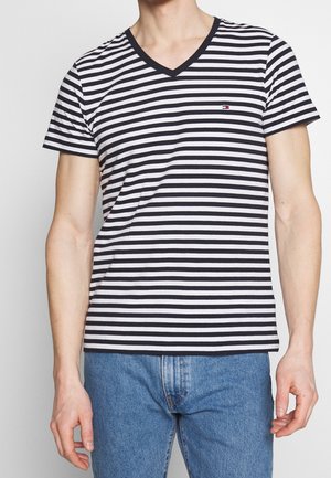 Męski T-shirt z dekoltem w serek w czarno-białe paski, krótkie rękawy, wykonany z bawełny, z małym logo na piersi. Luźny krój.