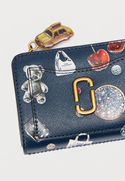 Portefeuille bleu marine avec surface texturée, présentant des imprimés colorés d'un ours en peluche, de cerises et d'une voiture. Détails en métal doré et tirette de fermeture éclair.