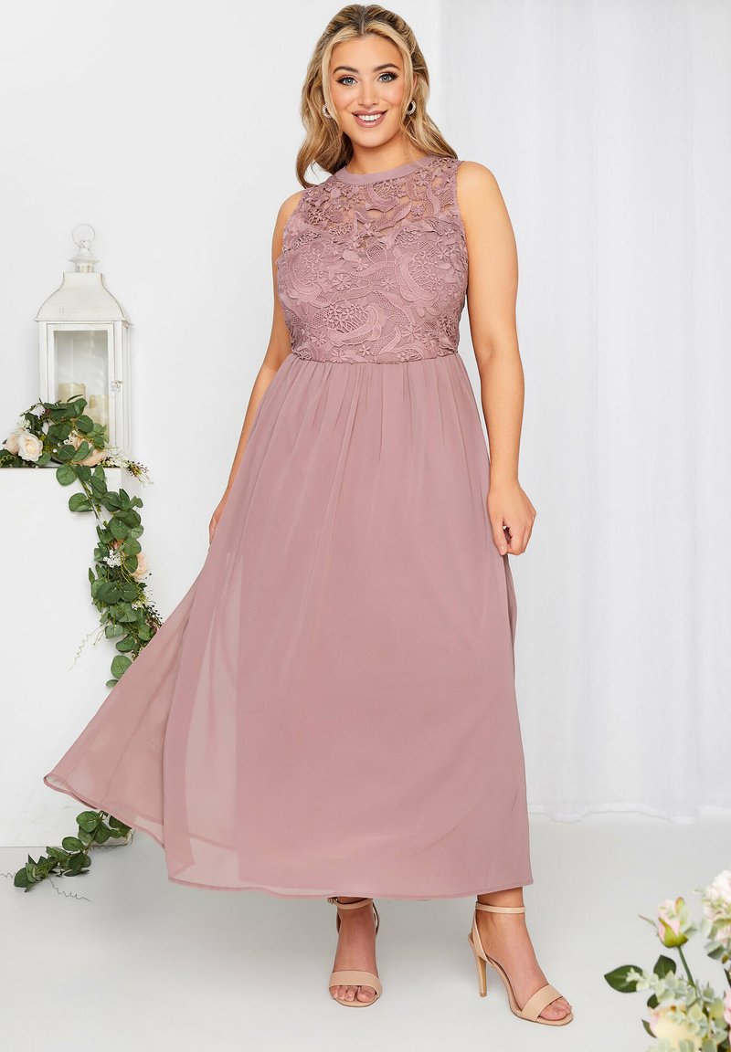 Długa, różowa sukienka w odcieniu blush z koronkowym gorsetem w kwiaty i zwiewną, warstwową spódnicą z szyfonu. Bez ramiączek i w fasonie A.