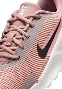 Nike tenisky s růžovým síťovaným svrškem, texturovanými akcenty a černým logem Swoosh. Podešev je bílá s mírným zakřivením a vzorkem.