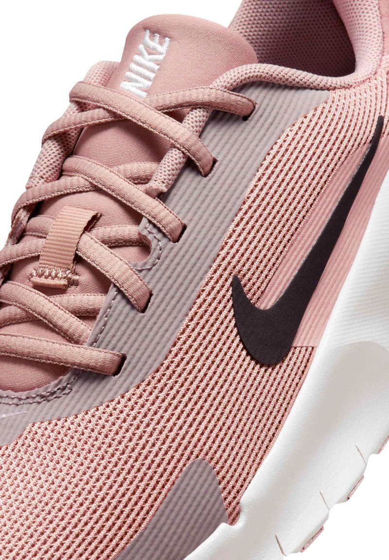 Nike sneakers with a pink mesh upper, textured accents, and a black Swoosh logo. The sole is white with a slight curve and tread.