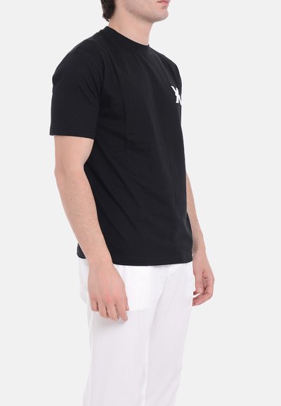 Maglietta nera in cotone con maniche corte e collo rotondo, caratterizzata da un logo bianco a contrasto sul lato sinistro del petto e un fit rilassato.